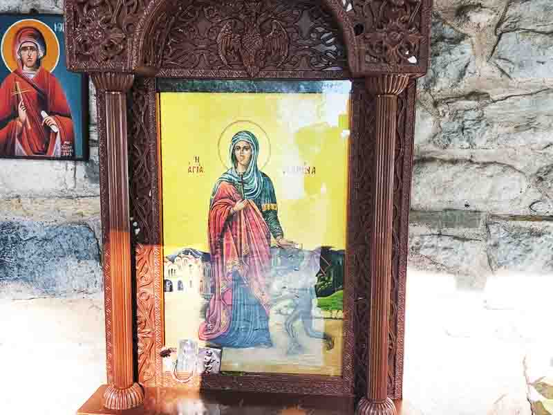 Agia Marina Rentina Αγία Μαρίνα Ρεντίνας: Ένα υστεροβυζαντινό θαύμα στα Μακεδονικά Τέμπη 2026 2 Εικόνα της Αγίας Μαρίνας μέσα σε ξυλόγλυπτο πλαίσιο, με φόντο πέτρινο τοίχο και δεύτερη μικρότερη εικόνα στα αριστερά.